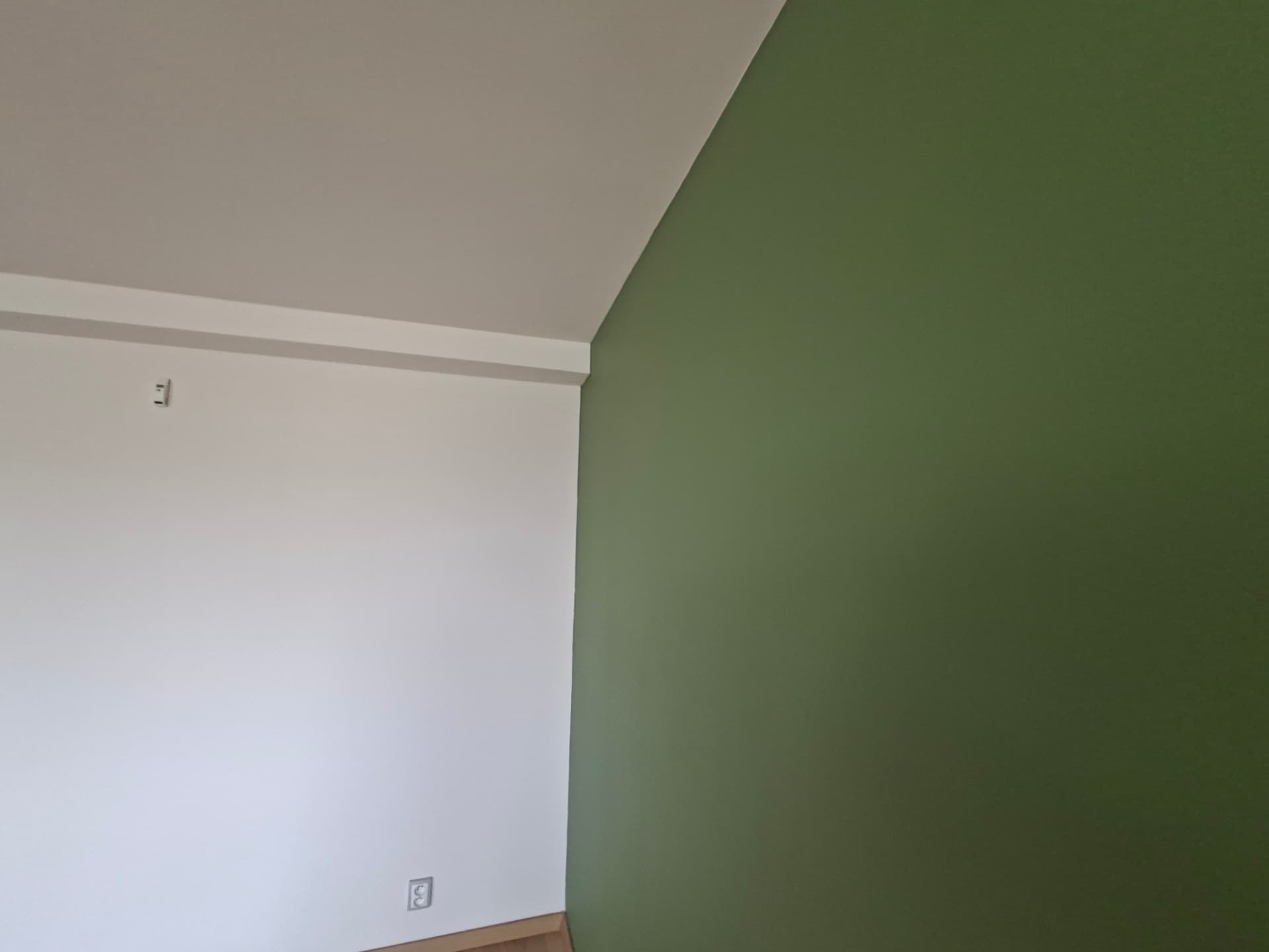 Detail přechodu bílého stropu a zelené stěny po výmalbě