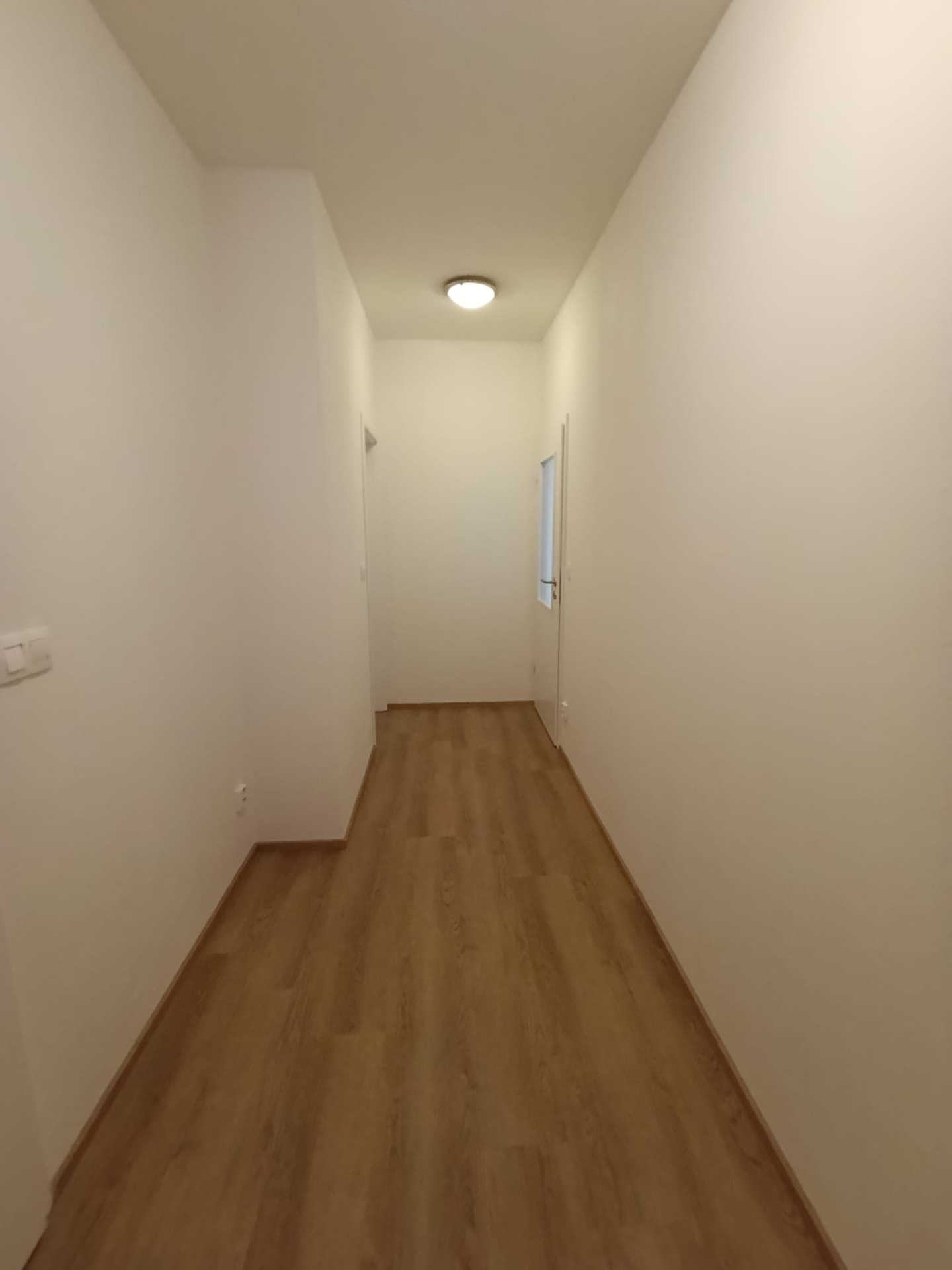 Předsíň po výmalbě bílou barvou v prázdném bytě na Praze 2